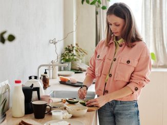 A woman slices an avocado in a bright, modern kitchen with natural light.